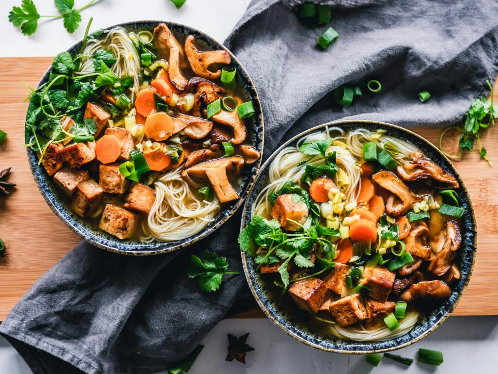 pexels-photo-3026808-3026808 A vibrant noodle bowl with tofu, mushrooms, and fresh vegetables, perfect for a healthy meal.